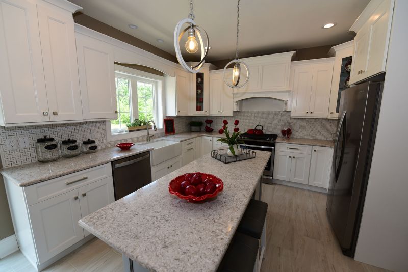Image of Kitchen featuring 9' ceilings, tile flooring, large island & white cabinets with granite countertops, large window behind the white farm sink & pendulum lighting over the island
