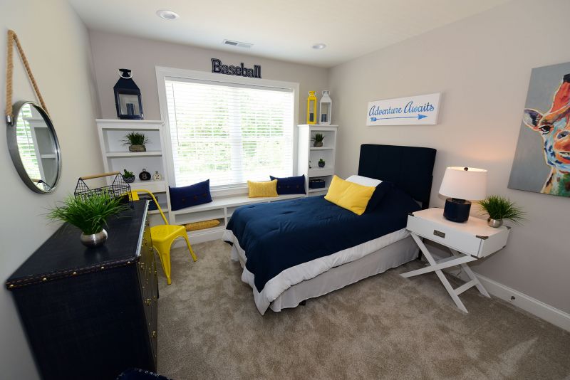 Image of back Bedroom fixed up for a boy featuring custom built-in shelving around and under the window creating a sitting area and wall to wall carpeting,