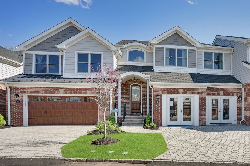Photo of the front of a typical building at Highland Cliffs, featuring vinyl siding and brick front exterior, and paver stone driveways.