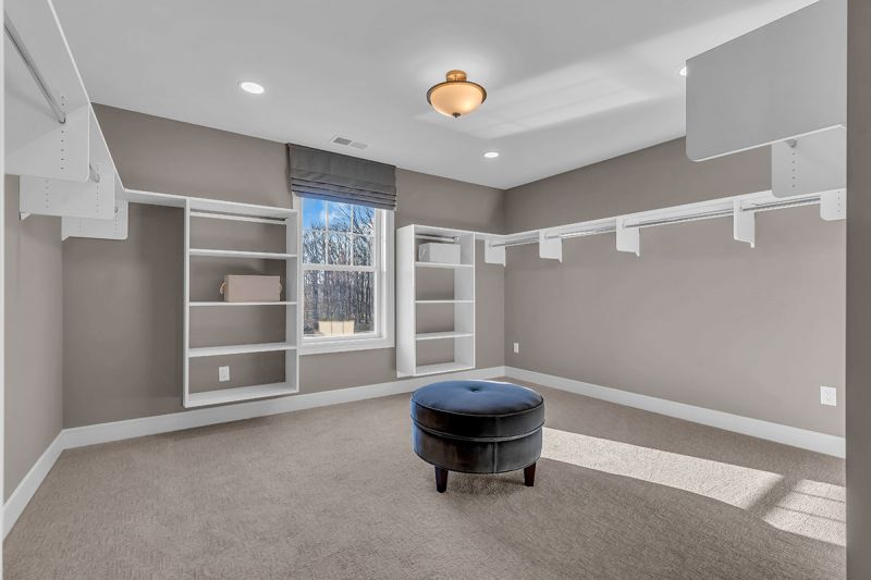 Interior photo of the Lockwood model at the Grove at Woodhaven showing a walk-in-closet featuring wall-to-wall carpeting and ample shelving. A large window brings in plenty of natural light.