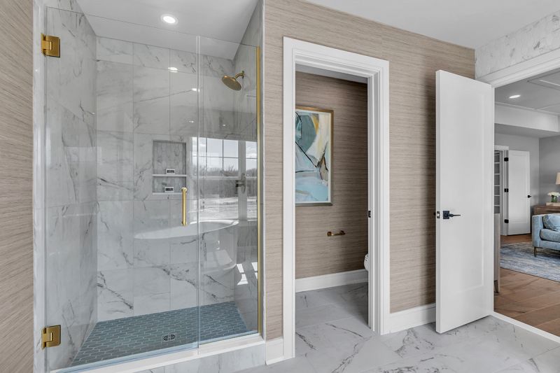 Interior photo of the Sequoia model at the Grove at Woodhaven showing the master bathroom featuring luxury marble flooring, a stand-up shower and a separate room with a toilet.